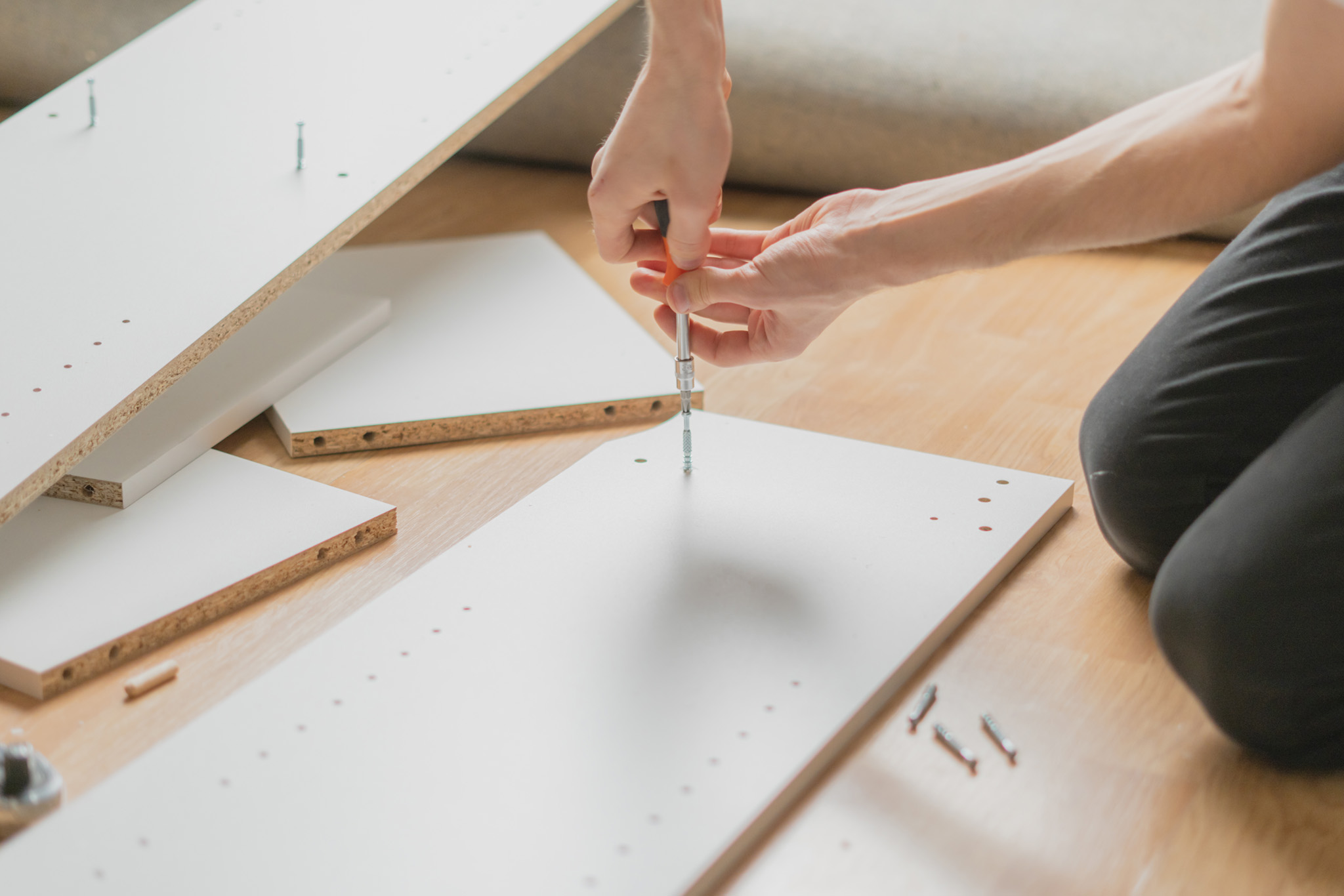 close up man assembling new furniture with a screwdriver